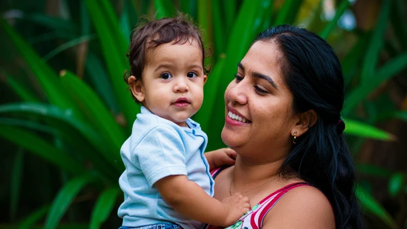 Madre mexicana sonríe con su hijo en un fondo vibrante